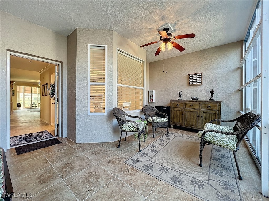 Living area featuring ceiling fan and a textured c