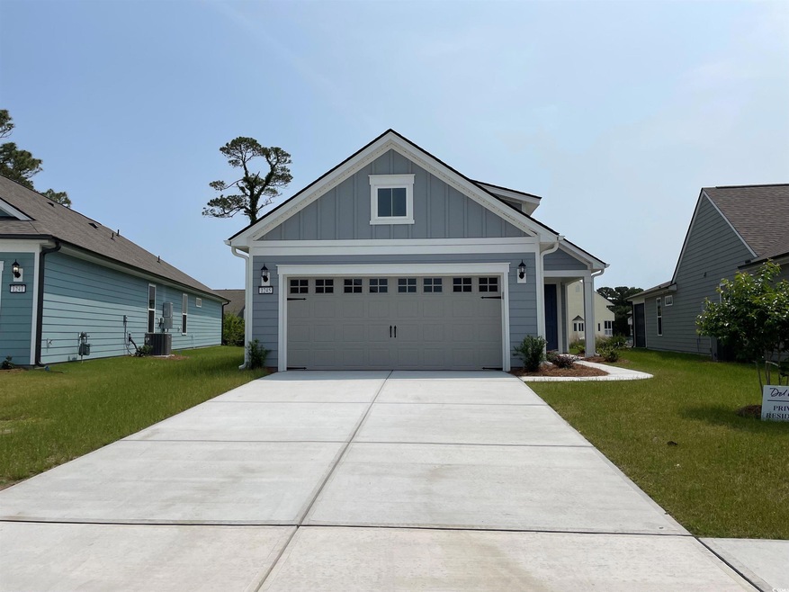 View of front facade with board and batten siding, a front yard, concrete driveway, central AC unit, and a garage