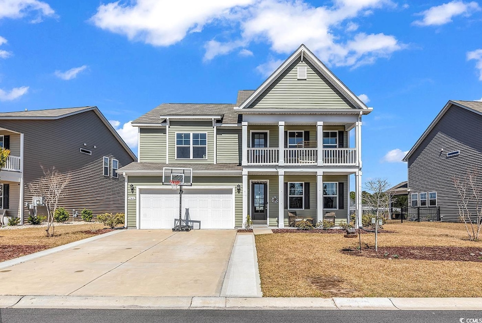 View of front of home featuring an attached garage, a balcony, covered porch, and driveway