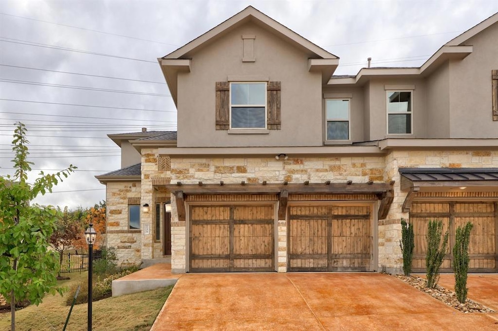 View of property featuring stone siding, a garage