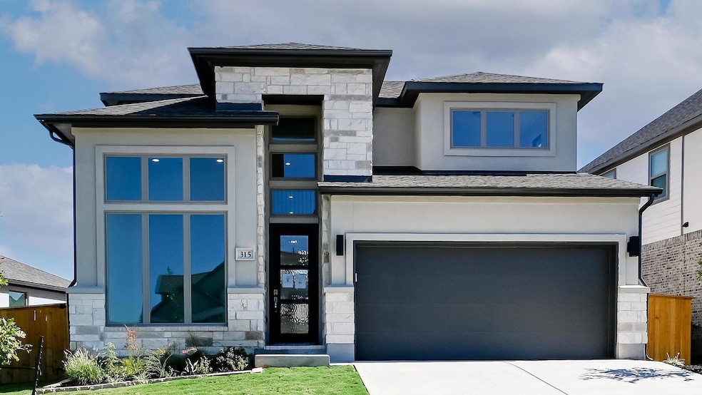 View of front facade featuring stone siding, a garage, a shingled roof, and concrete driveway