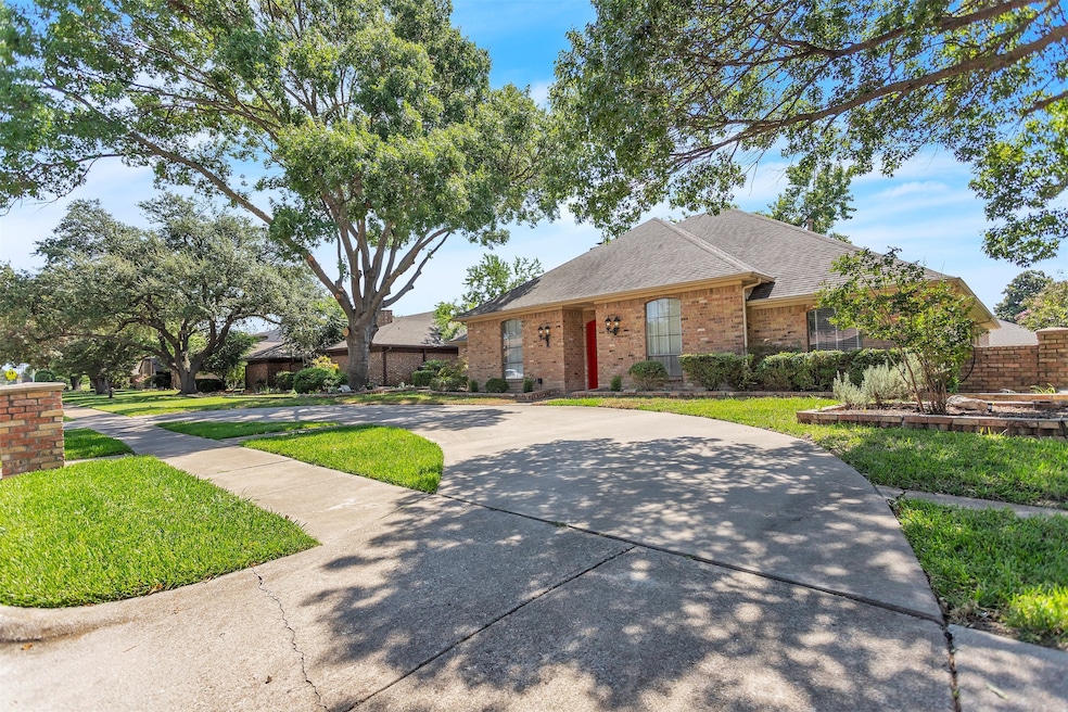 Ranch-style home featuring a shingled roof, brick siding, a front yard, and concrete driveway