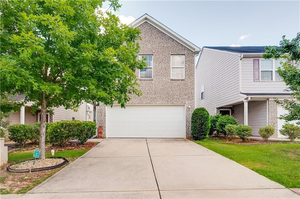 View of front of property with a garage, brick siding, driveway, and a front lawn