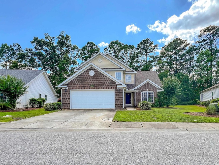 Traditional-style home with brick siding, an attached garage, a front lawn, and driveway