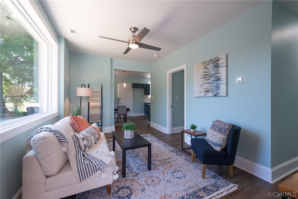 Living room with ceiling fan and dark wood-type fl