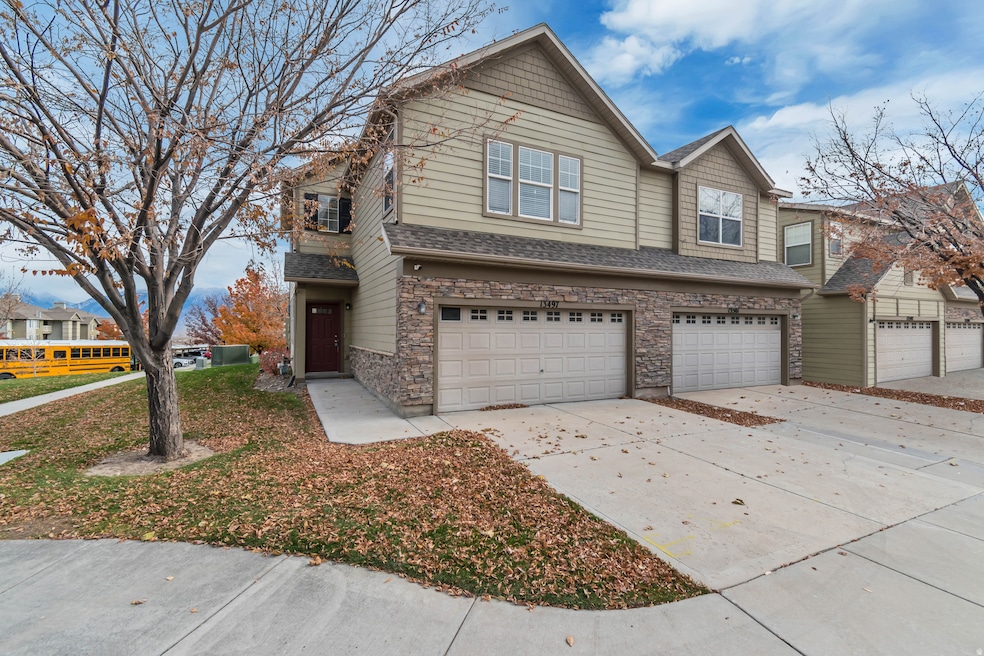 View of front of home featuring driveway, stone siding, an attached garage, and a shingled roof
