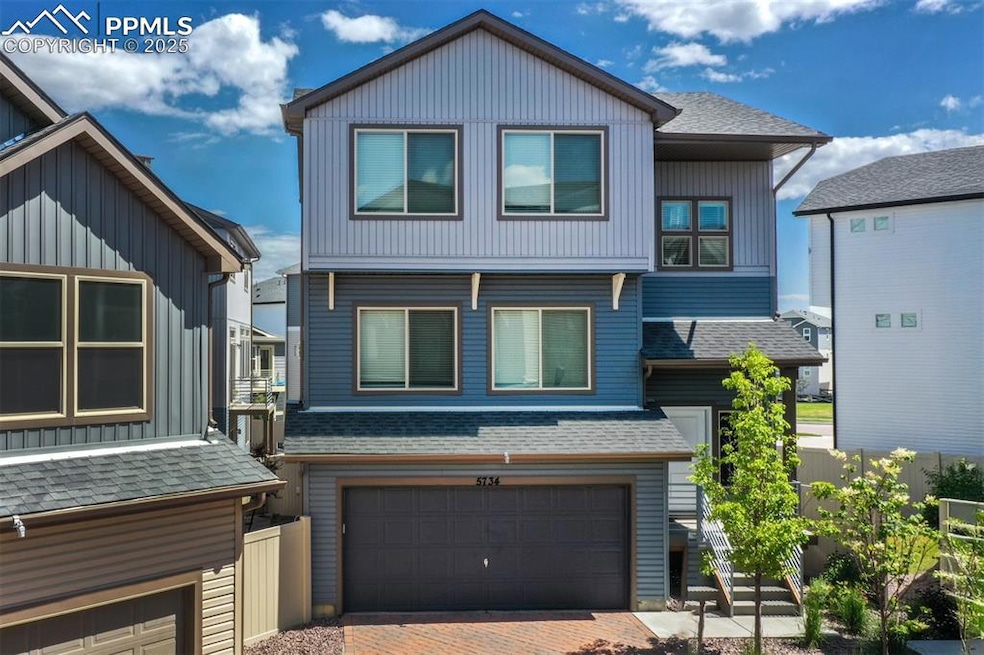 View of front facade featuring a garage, roof with shingles, and decorative driveway