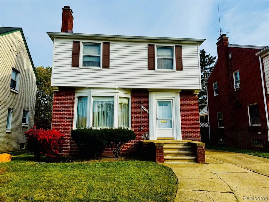 Colonial home with brick siding, a front yard, and a chimney