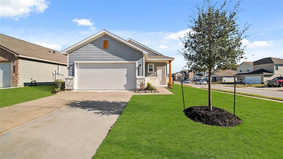 View of front facade featuring concrete driveway, a front yard, and stone siding