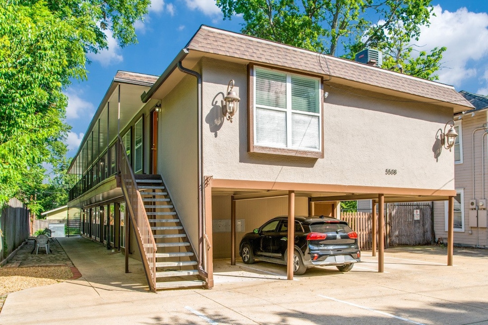 View of front of house featuring stairs, roof with shingles, stucco siding, a carport, and mansard roof