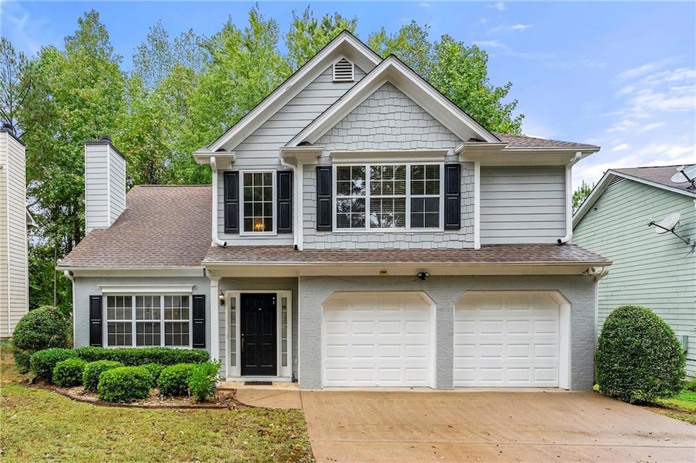 View of front of home featuring roof with shingles, concrete driveway, an attached garage, and a chimney