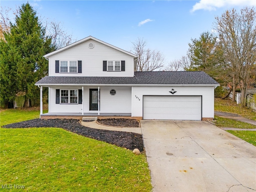 Traditional home with covered porch, concrete driveway, a garage, a front lawn, and roof with shingles