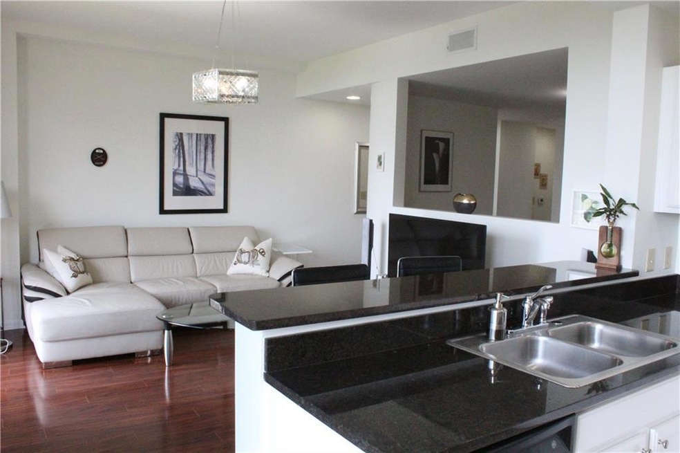 Kitchen with dark countertops, a sink, open floor plan, dark wood-style floors, and white cabinetry