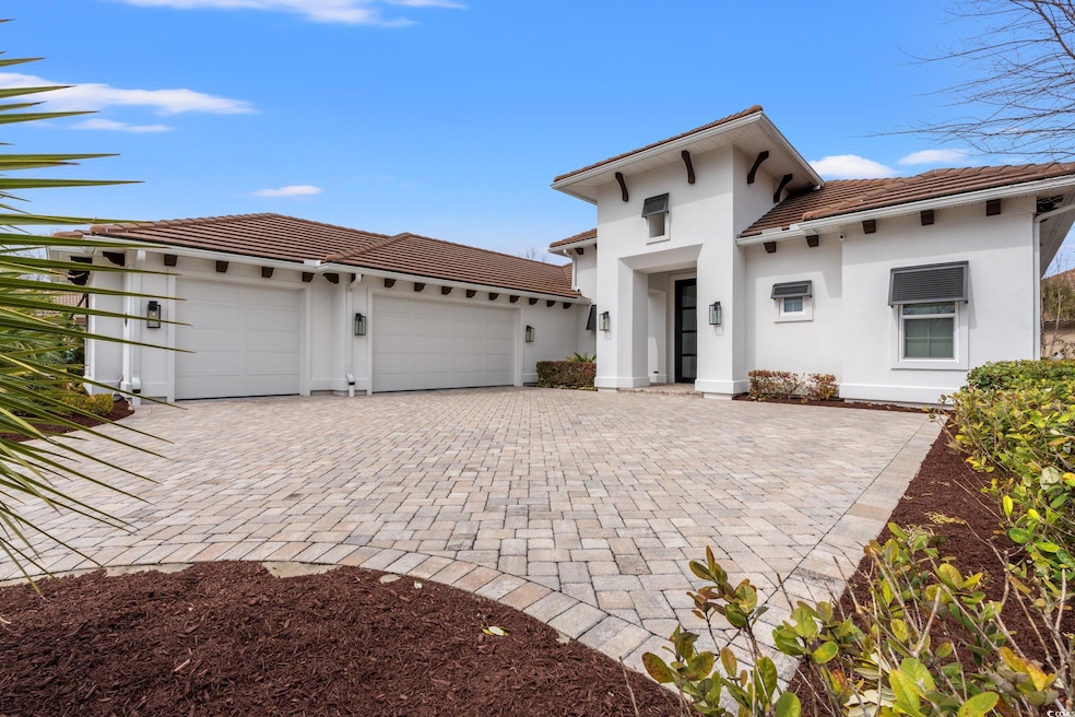 View of front of house featuring decorative driveway, a tiled roof, an attached garage, and stucco siding