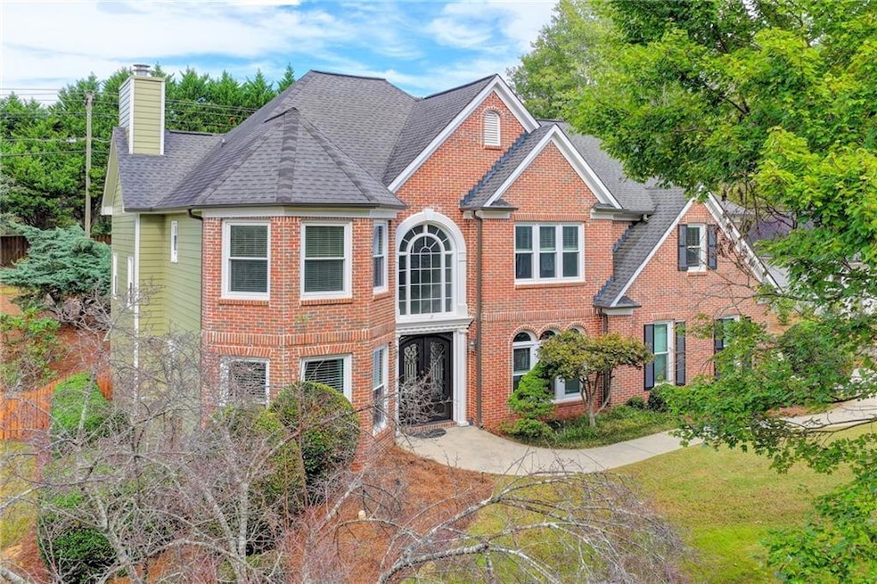 View of front facade with a chimney, brick siding, a shingled roof, and a front lawn