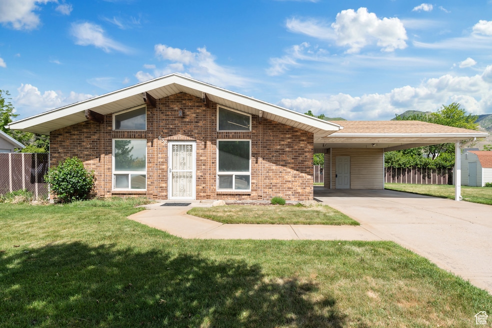 Mid-century modern home with brick siding, driveway, and an attached carport