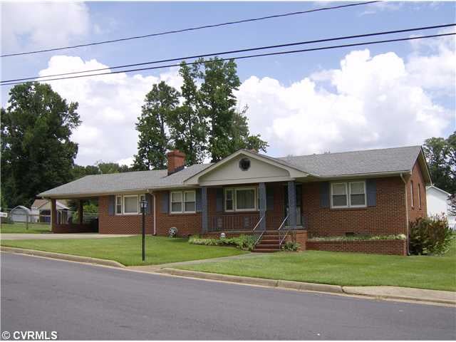 Exterior Front - Brick with concrete & brick front porch, built-in flower box, carport w/ double width paved driveway, concrete sidewalk, yard light, curb and gutter street.