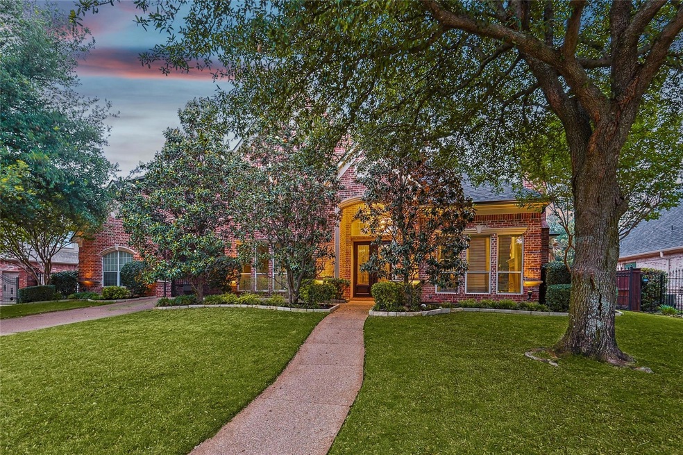 View of front facade featuring trees and view of the gated drive area.