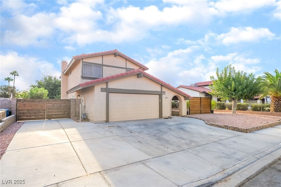 Mediterranean / spanish house with a tile roof, concrete driveway, stucco siding, a gate, and a chimney