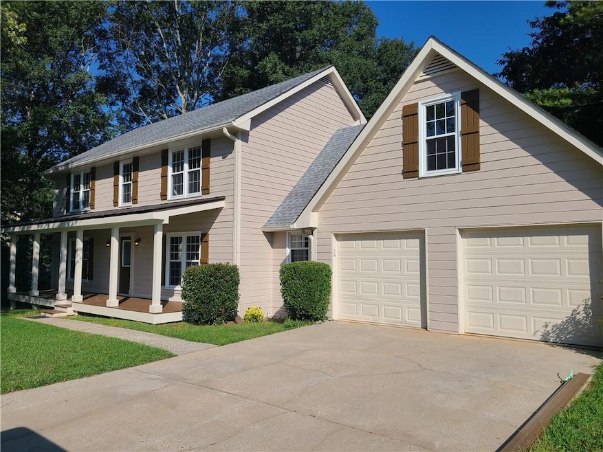 Beautiful frontal view of property featuring newly built and painted covered front porch and seating area, 2-car garage, elongated driveway, and a landscaping.