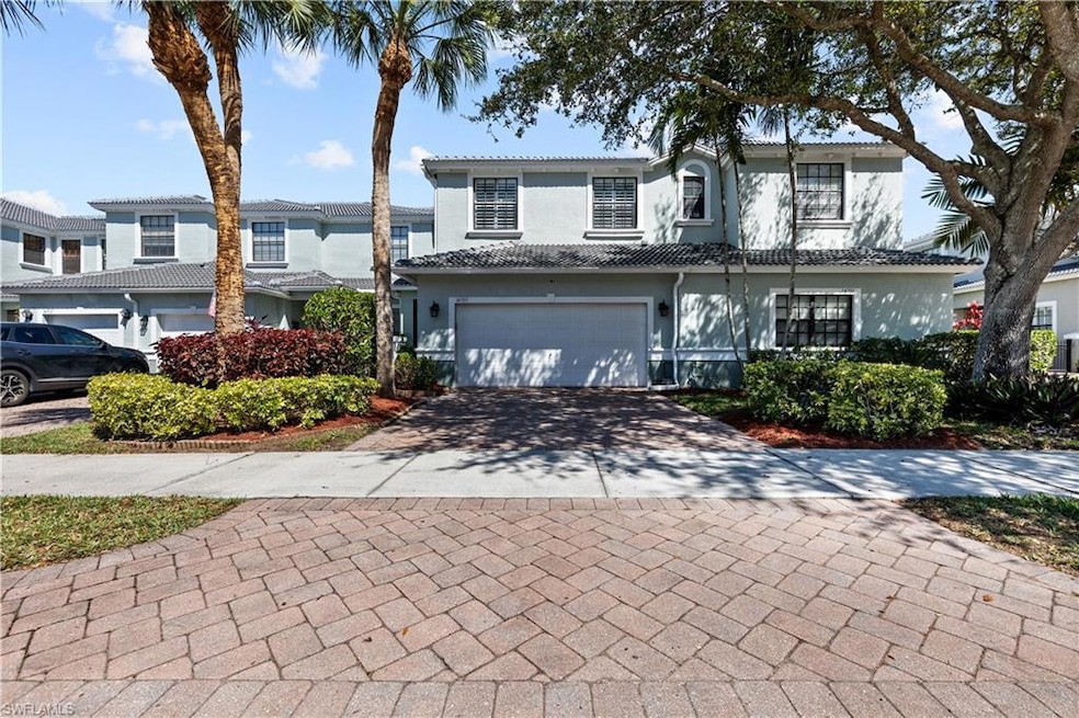 Traditional-style home featuring an attached garage, a tiled roof, driveway, and stucco siding
