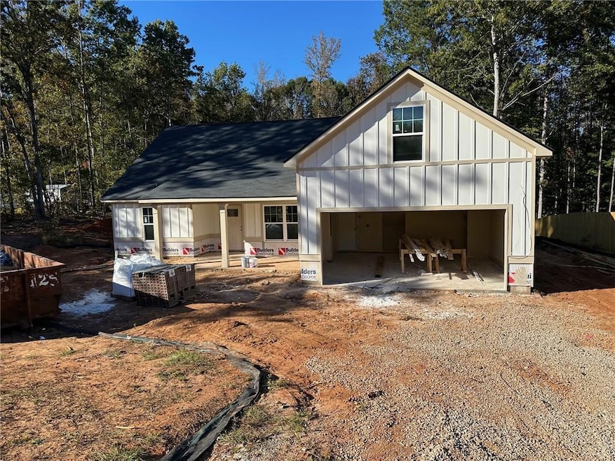 View of front of house with board and batten siding, a shingled roof, a garage, a porch, and driveway