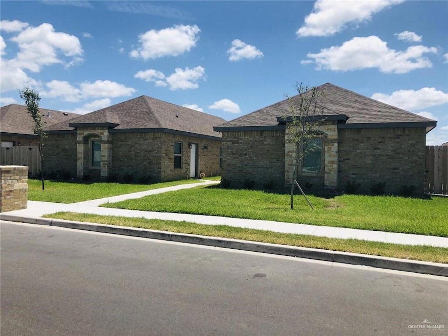 View of front of house with brick siding, a front lawn, and fence