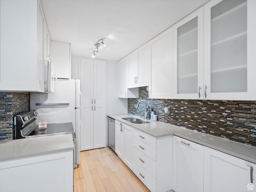 Kitchen with white cabinetry, glass insert cabinets, and light stone countertops