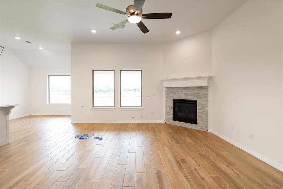 Kitchen featuring open floor plan, light wood-style flooring, white cabinets, vaulted ceiling, and light countertops