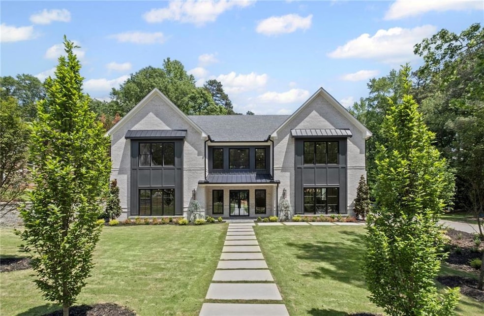 Rear view of house with a standing seam roof, a lawn, a shingled roof, and metal roof