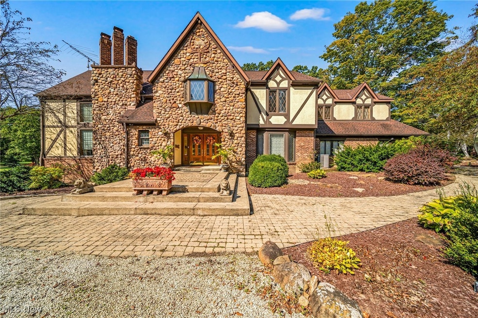 Tudor home featuring a chimney, stucco siding, french doors, and stone siding