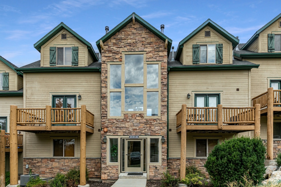 Back of property featuring a balcony, stone siding, and french doors