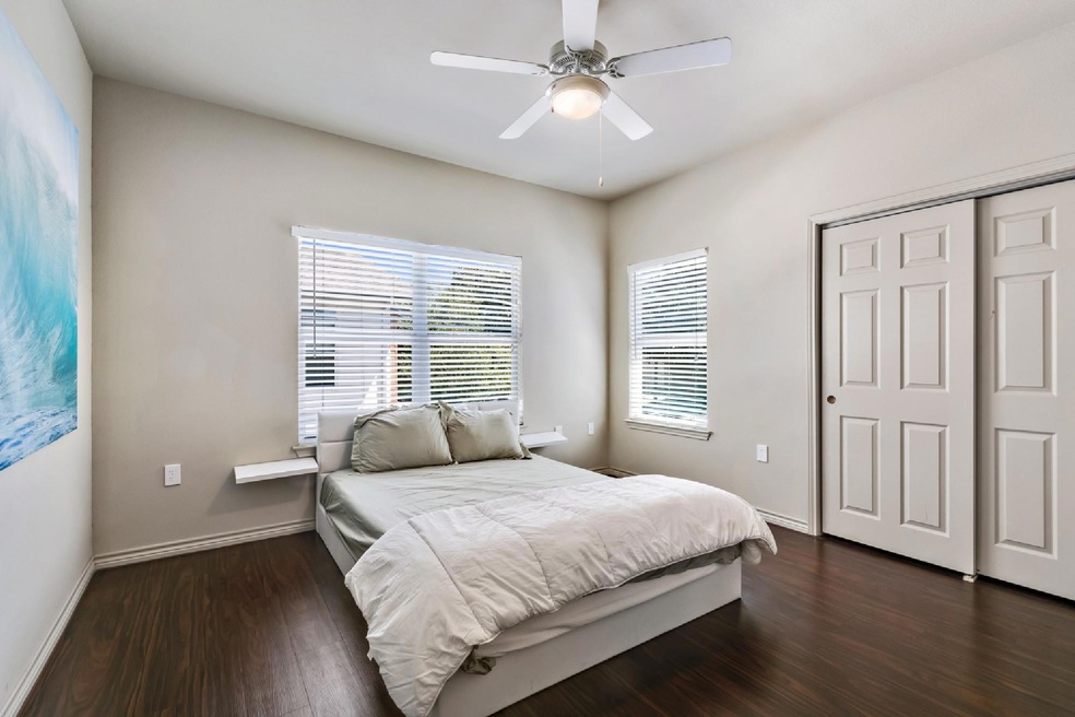Bedroom with multiple windows, dark wood-style fl