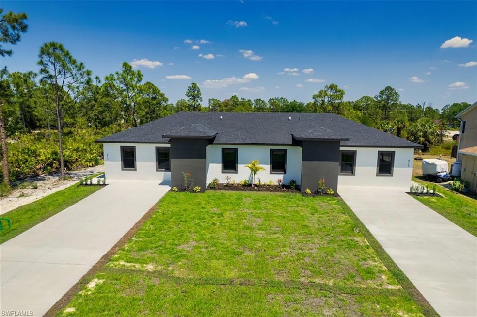 View of front of house featuring driveway, stucco siding, and a front lawn