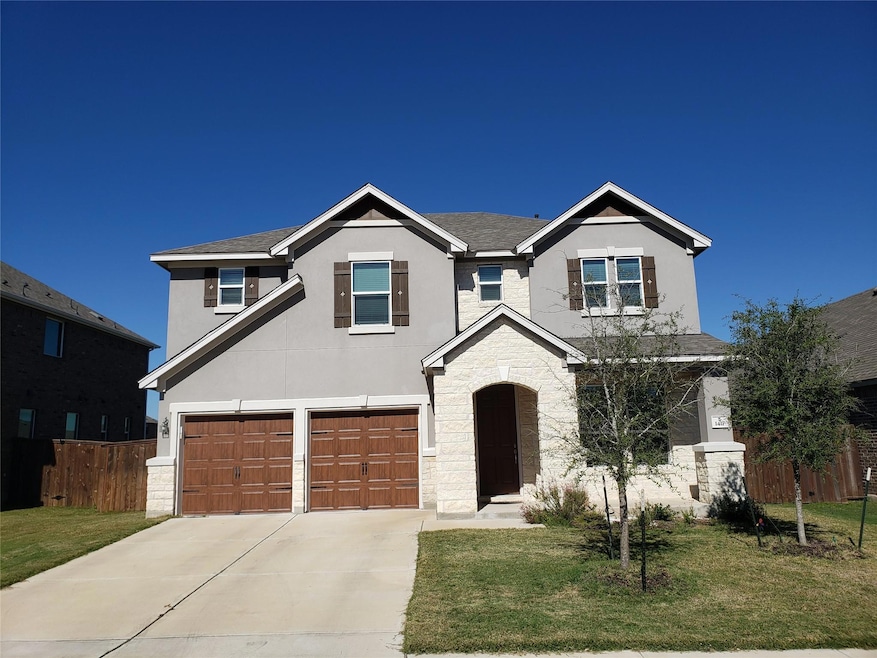 Traditional home featuring stone siding, stucco siding, an attached garage, driveway, and roof with shingles