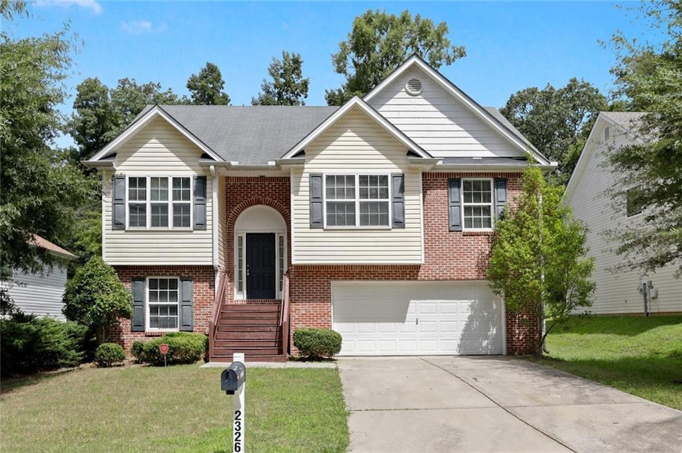 Bi-level home featuring brick siding, concrete driveway, a front yard, and a garage