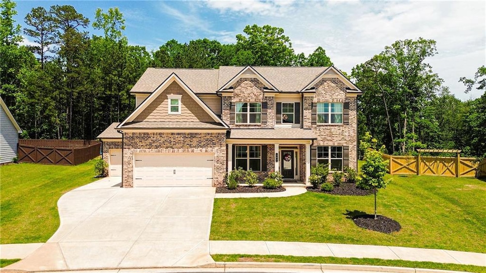 Craftsman-style house featuring brick siding, a gate, driveway, and an attached garage