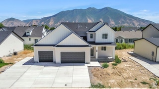 View of front of property with a residential view, a mountain view, concrete driveway, and an attached garage