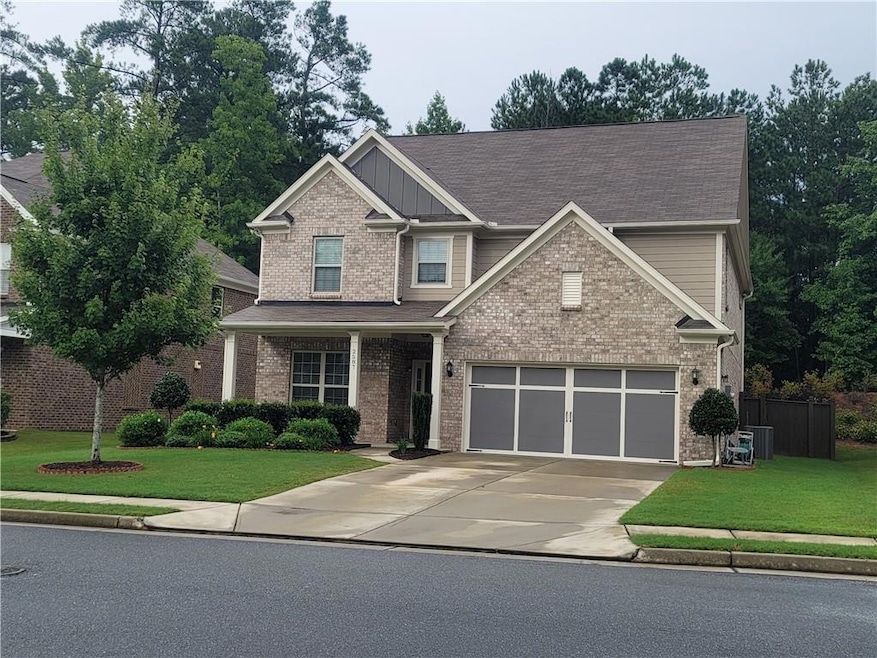 Craftsman-style home featuring a front yard, concrete driveway, and brick siding