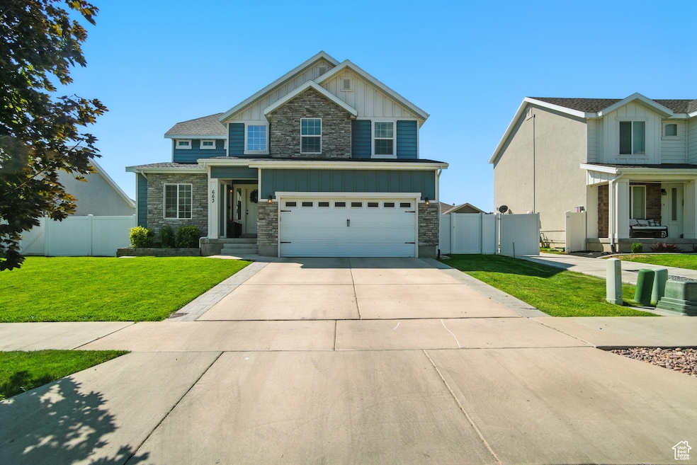 Craftsman-style home with board and batten siding, stone siding, driveway, covered porch, and an attached garage