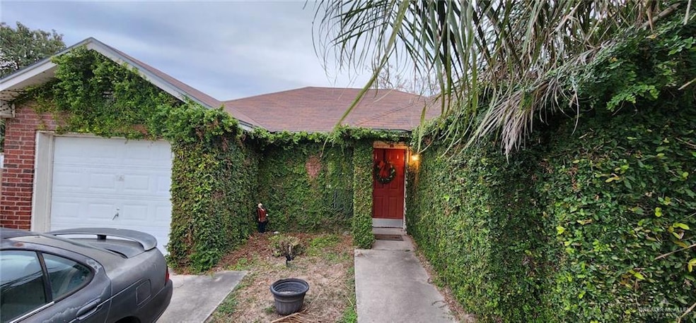 View of property hidden behind natural elements featuring a garage