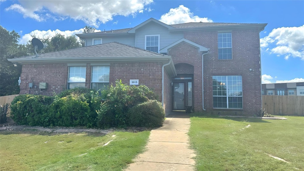 Traditional-style house with a shingled roof, a front yard, fence, and brick siding