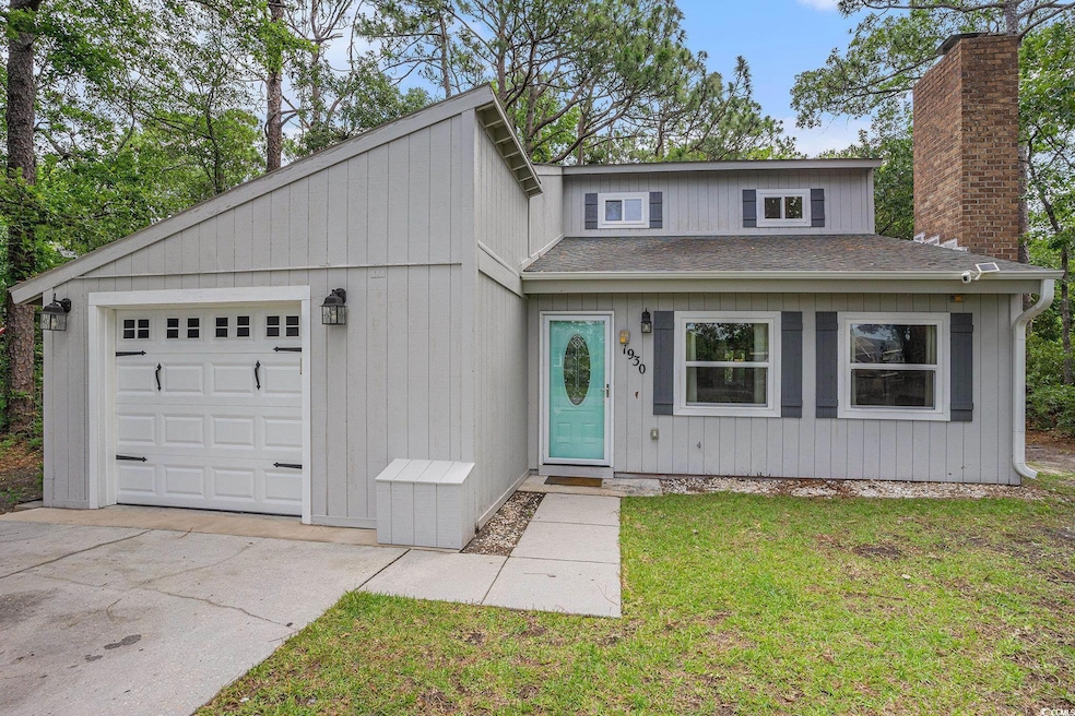 View of front of home featuring a shingled roof, a chimney, a garage, a front lawn, and driveway
