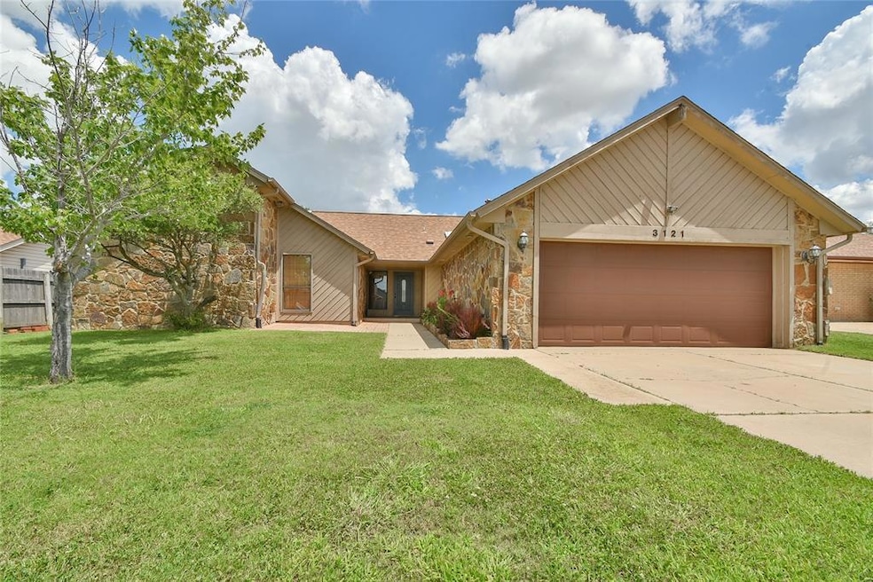 View of front of property featuring stone siding, an attached garage, and driveway