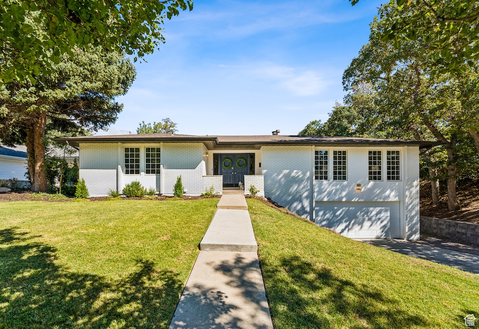 Ranch-style home with brick siding, a front lawn, and an attached garage