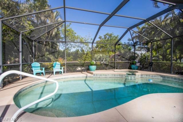 View of swimming pool with a pool with connected hot tub, a patio, and a lanai
