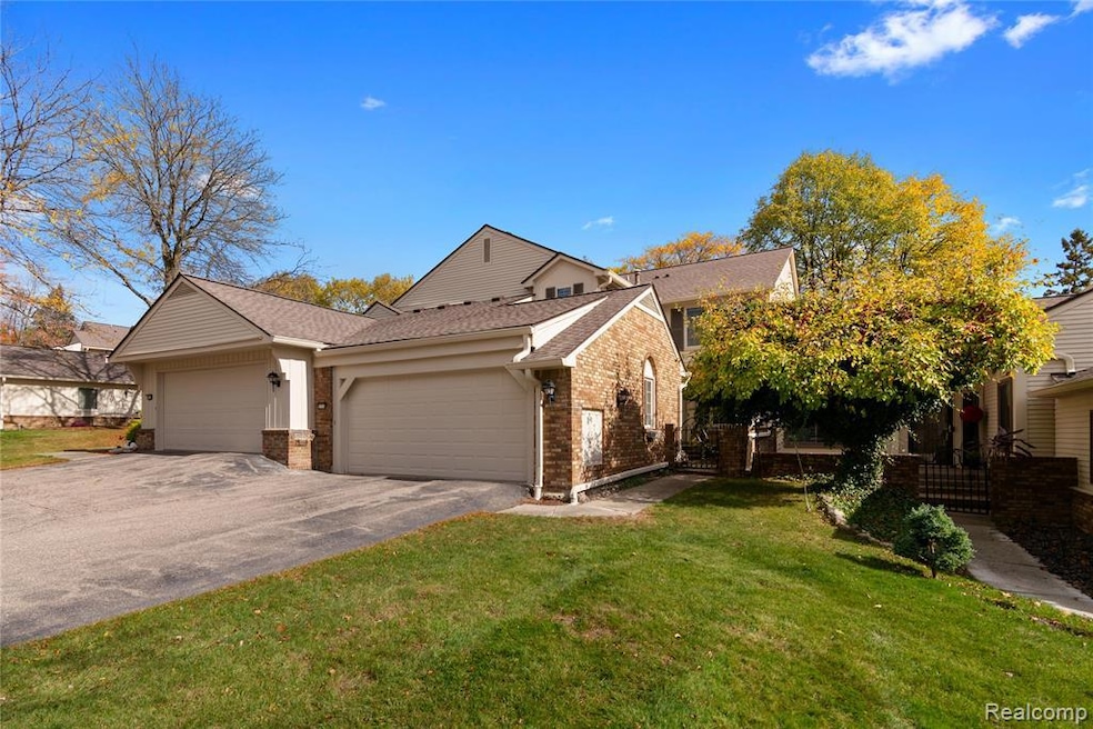 View of front facade featuring brick siding, an attached garage, driveway, and a shingled roof