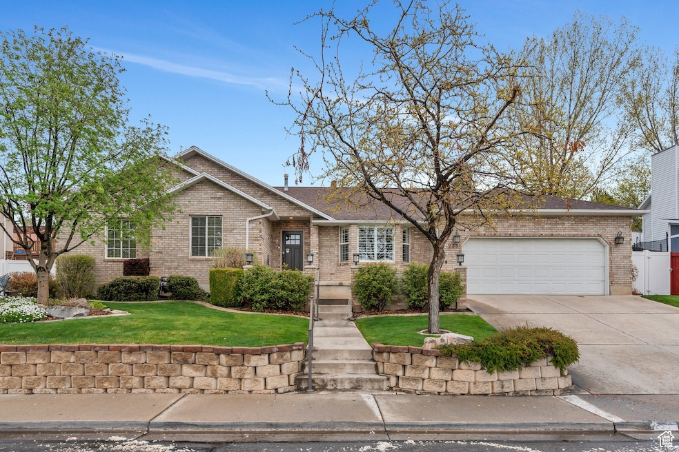 View of front of home featuring a front yard, concrete driveway, brick siding, and a garage