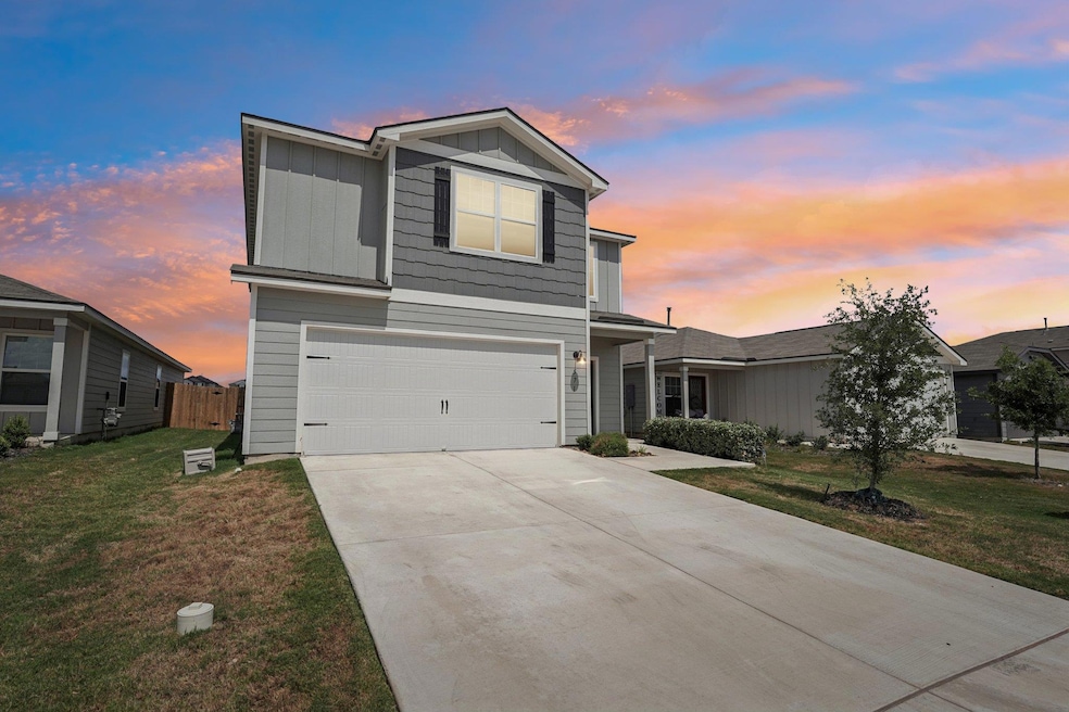 Traditional-style home featuring board and batten siding, an attached garage, driveway, and a yard