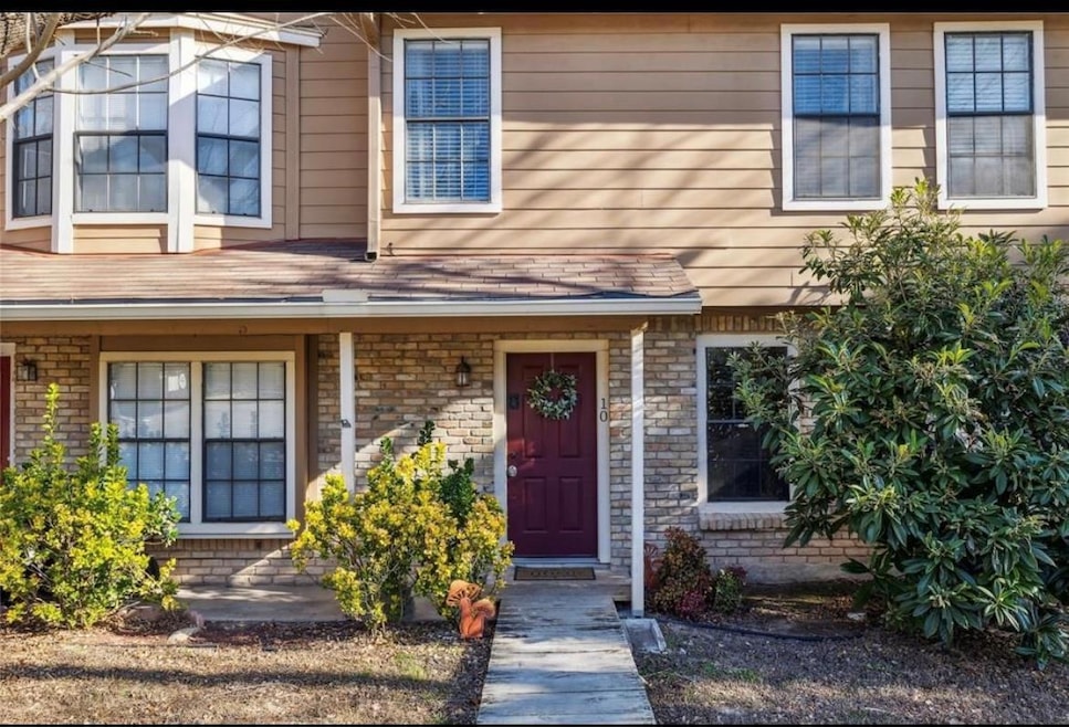 Welcome home to this charming two-story residence with a warm brick facade, inviting red front door, and lush landscaping that offers great curb appeal. A private walkway leads you inside.